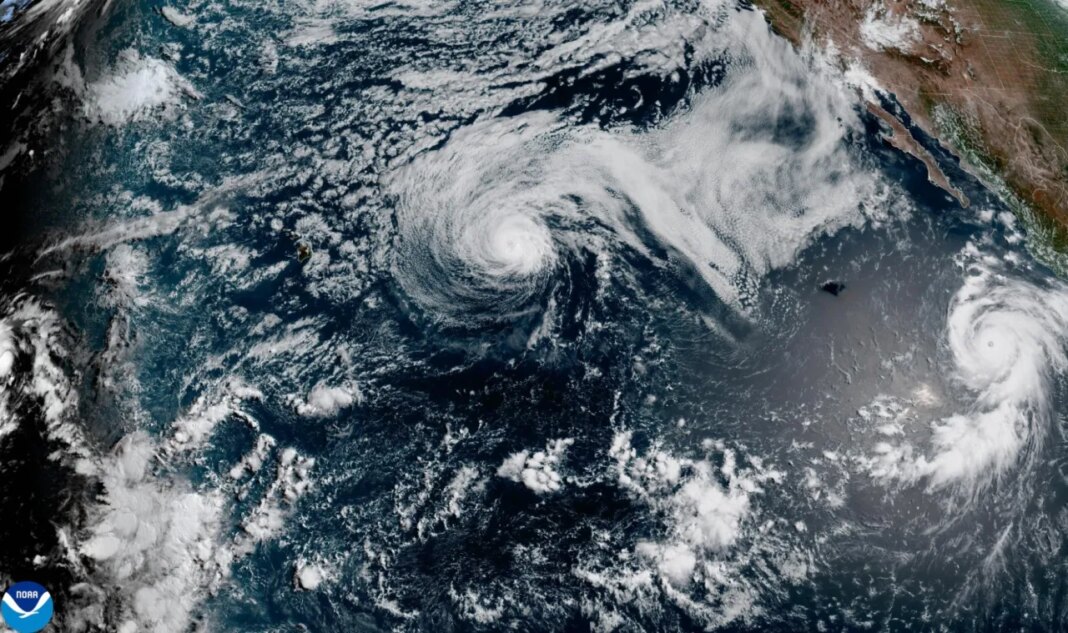 This satellite image released by NOAA shows Hurricane Fausto, center, and Hurricane Genevieve off the southwest coast of Mexico, right, over the Pacific Ocean, Sunday, July 26, 2026. (NOAA via AP)