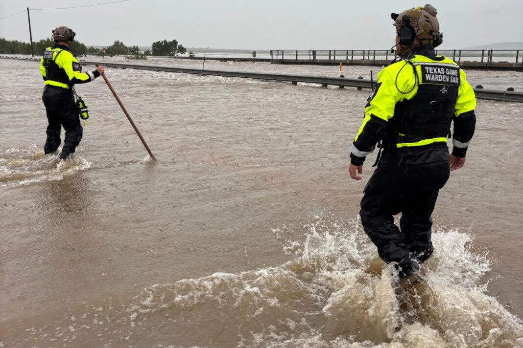In this handout photo provided by the Texas Parks and Wildlife Department, game wardens walk through high waters from heavy rains in Uvalde County, Texas, on Tuesday, July 14, 2026. (Texas Parks and Wildlife Department via AP)
