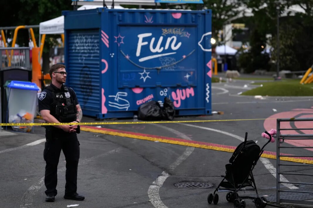 A police officer stands at a closed off area after a shooting at Seattle Center during the Bite of Seattle food festival Sunday, July 26, 2026, in Seattle, Wash. (AP Photo/Lindsey Wasson)