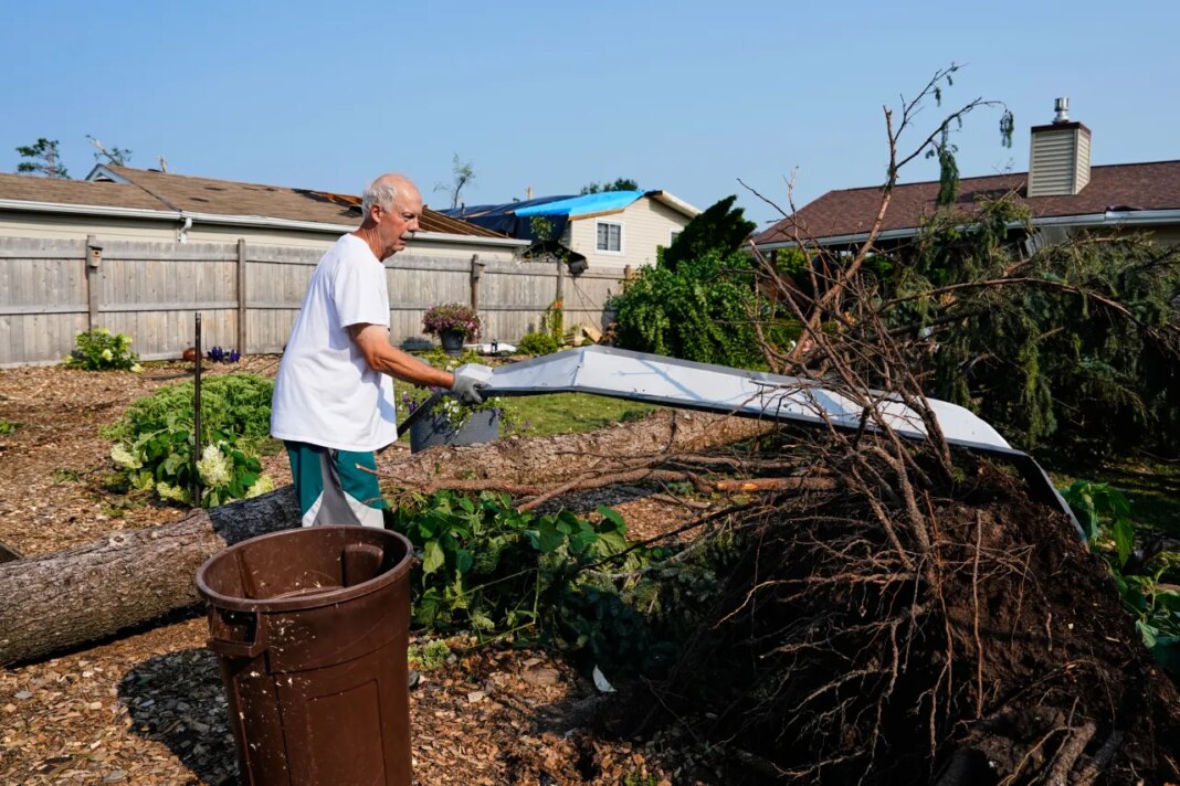 Williams Burrows cleans up debris in his backyard after a tornado struck the day before, Tuesday, July 28, 2026, in Appleton, Wis. (AP Photo/Kayla Wolf)