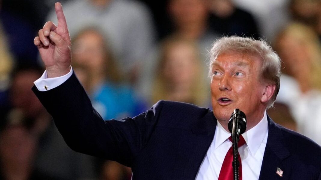 Donald Trump points with his right pointer finger into the air at a rally.