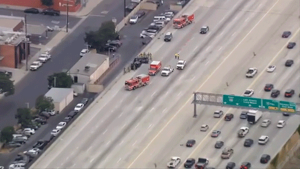 Emergency crews respond to two overturned cars on the 405 Freeway as traffic moves past the crash scene