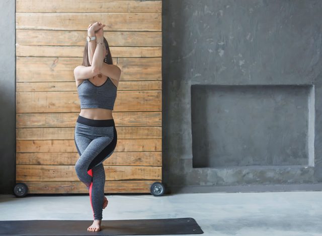 Woman in yoga class making asana exercises, copy space. Girl do eagle pose, garudasana. Healthy lifestyle in fitness club. Stretching