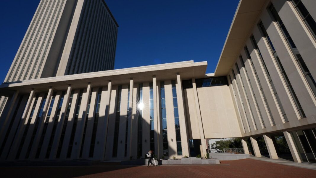 A person walks in front of the Florida Capitol, during a legislative session in Tallahassee, Fla., Thursday, March 6, 2025. (AP Photo/Rebecca Blackwel
